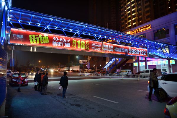 Sales and rental advertisement for retail shops plastered on the side of a footbridge outside the mega real estate project Huaguoyuan in Guiyang.