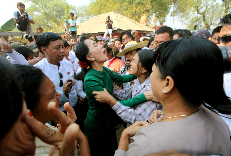 Aung San Suu Kyi talks with crying villagers during a visit to Tone village AP