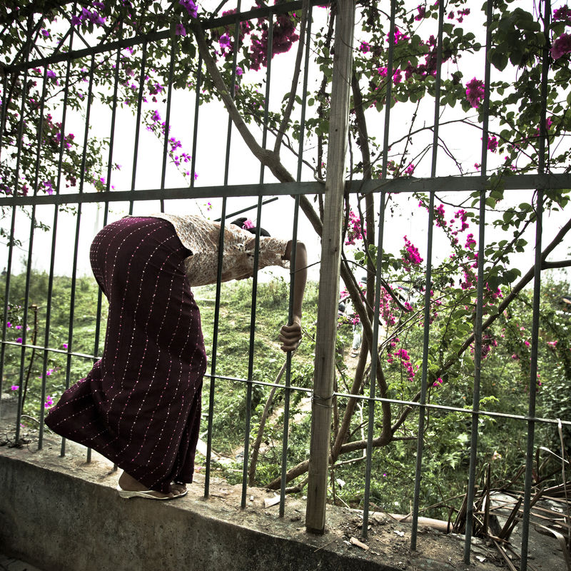 A woman slips through an opening in the fence separating China from Myanmar PIERO VIO SCMP