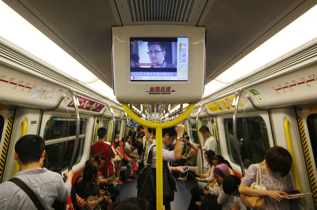 Train passengers watch news of Edward Snowden, the US whistle-blower who is hiding in Hong Kong. Photo: Reuters