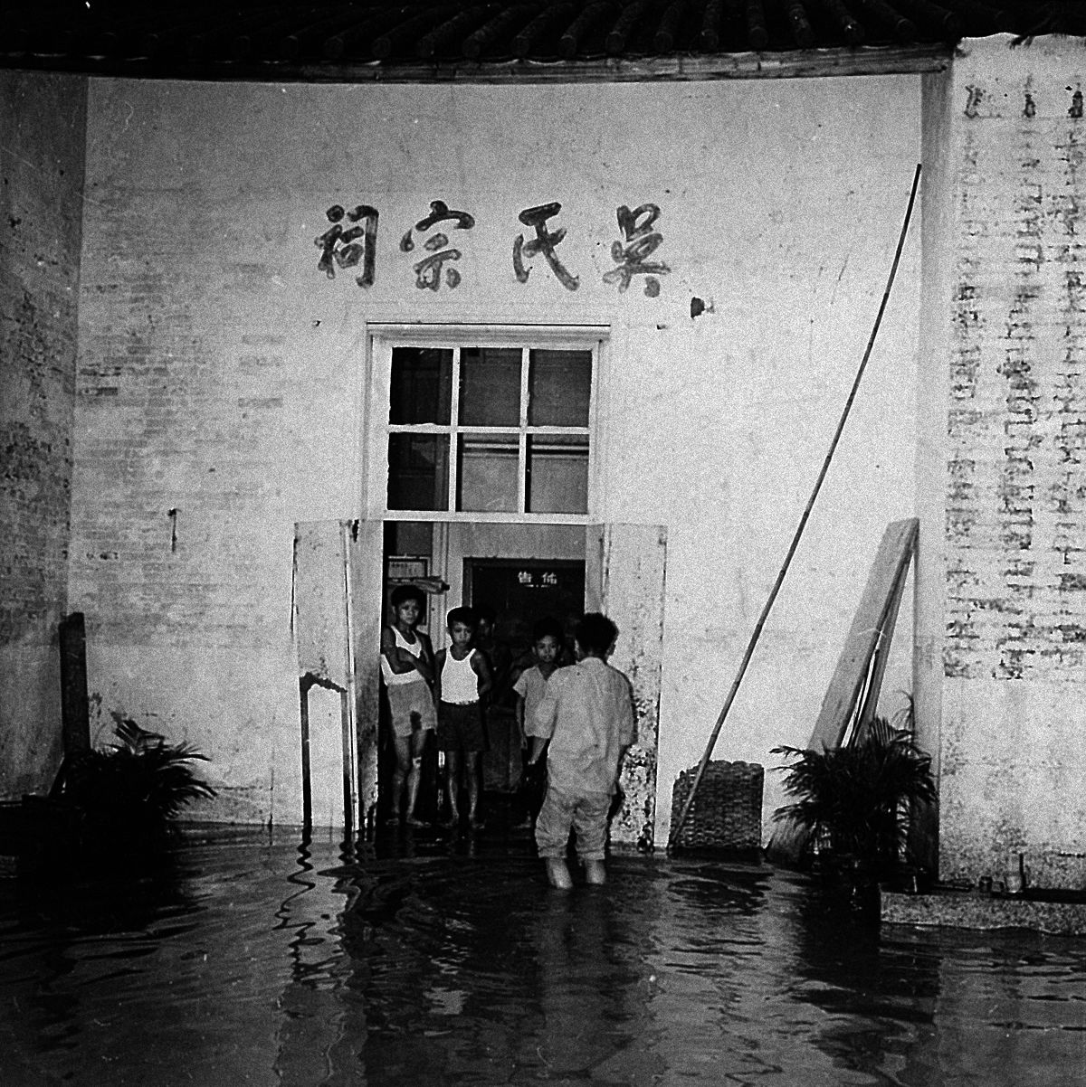 A family looks out at floods brought by Typhoon Wanda